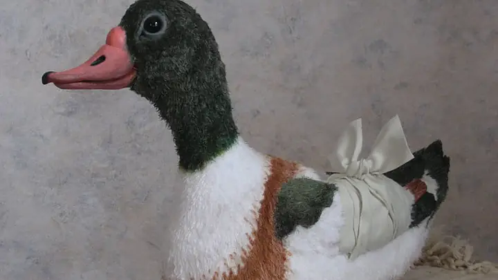 Finished hand puppet duck with a pink bill, sitting on folded linen